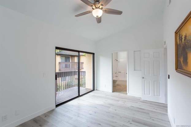 An empty room with a ceiling fan and sliding glass doors