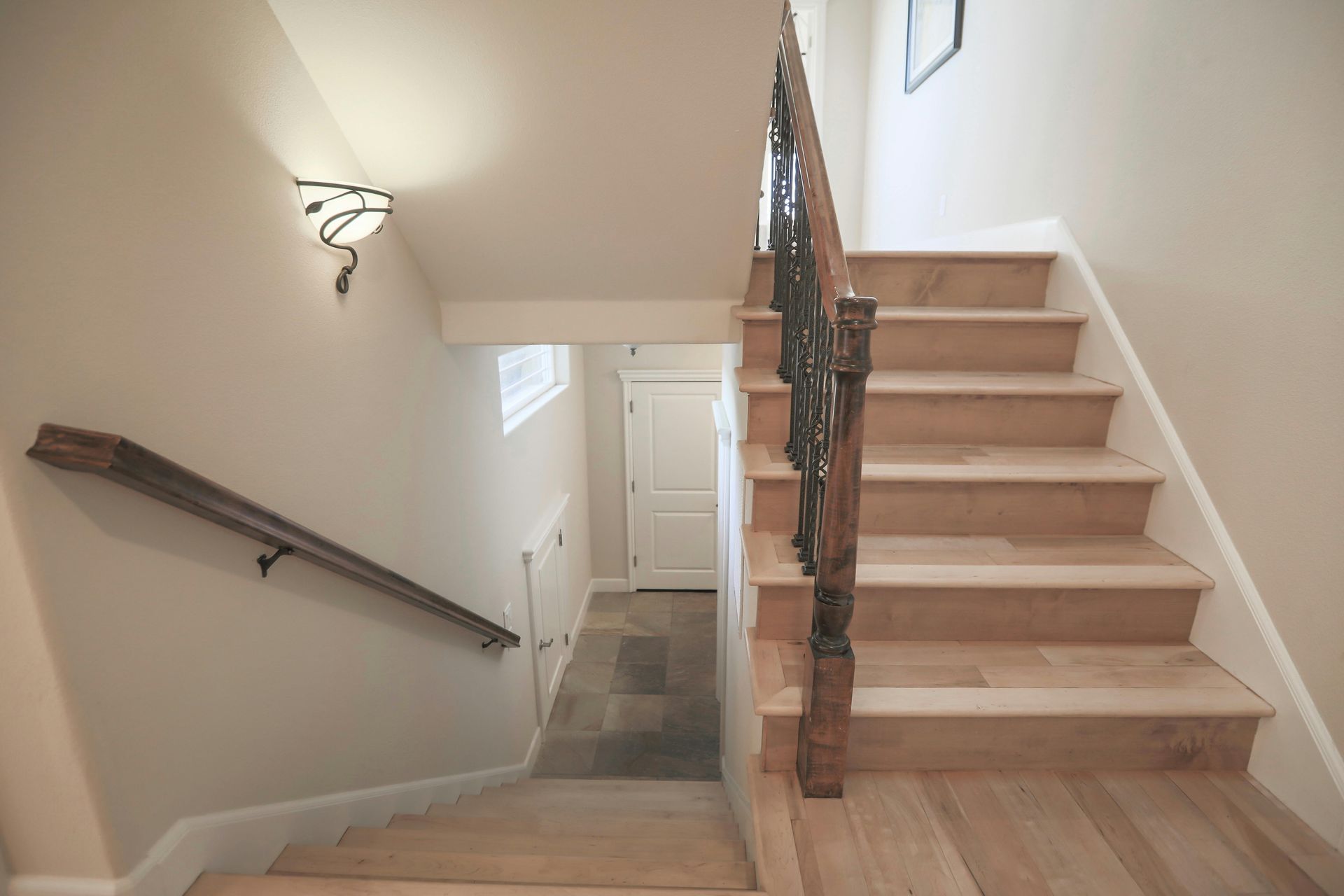 A wooden staircase with a metal railing leading up to the second floor of a house.