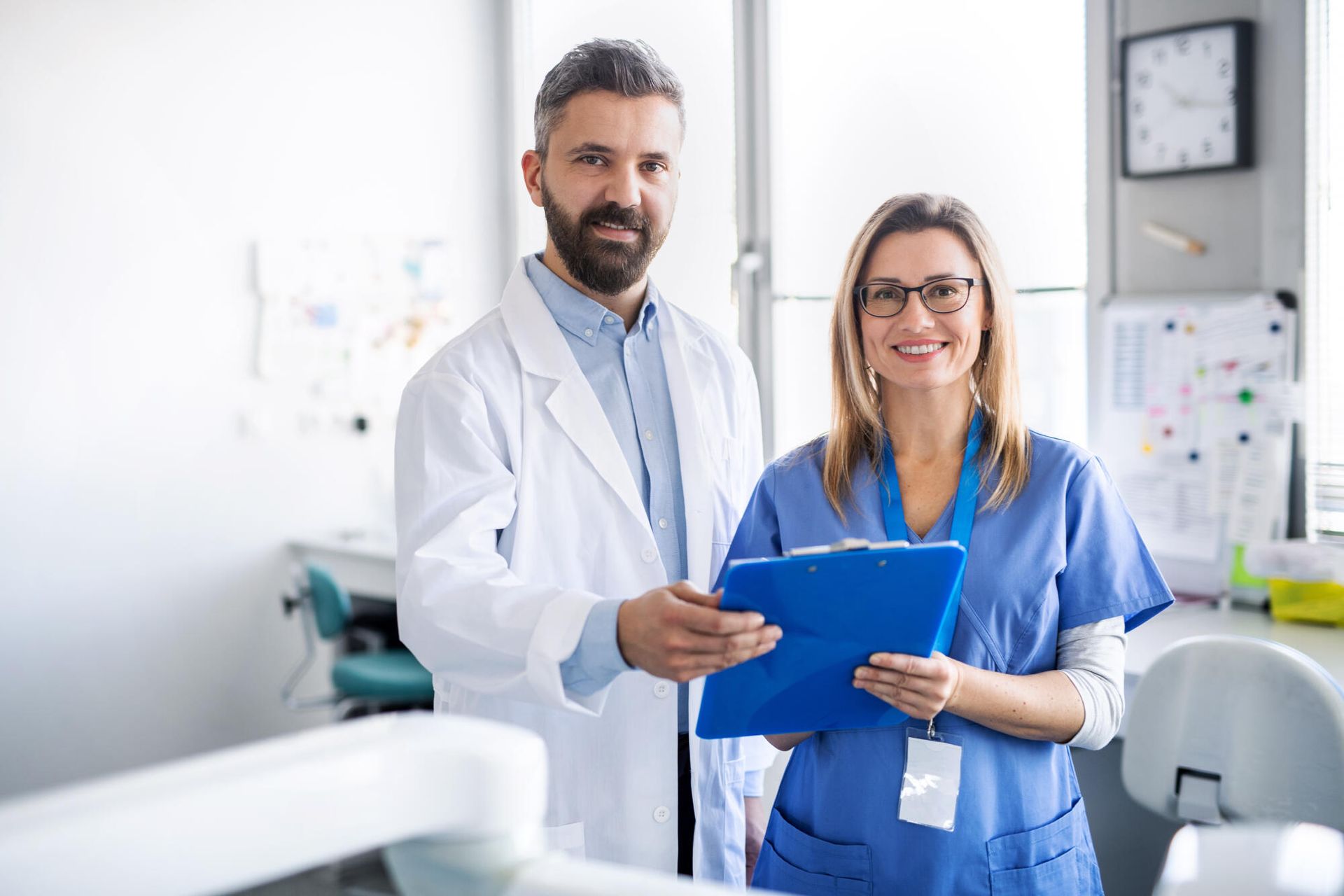 A man and a woman are standing next to each other in a hospital holding a clipboard.
