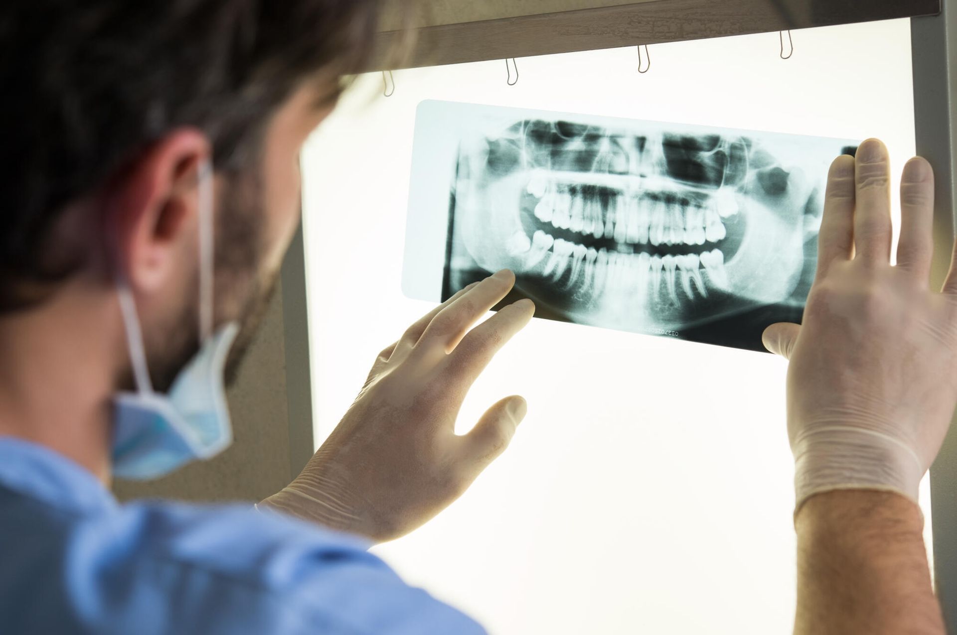 a dentist is looking at an x-ray of a person 's teeth .