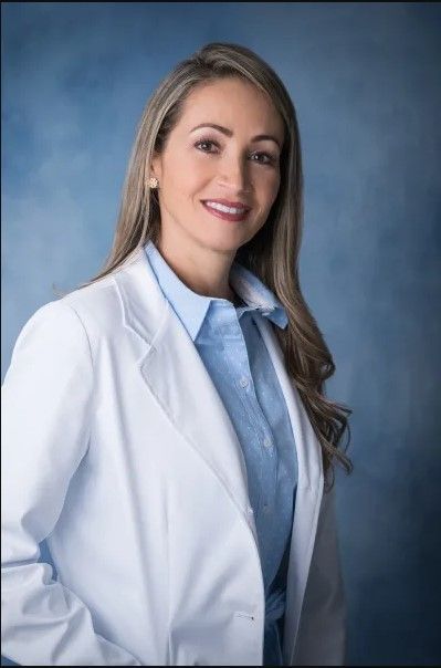 A woman is wearing a white lab coat and a blue shirt.