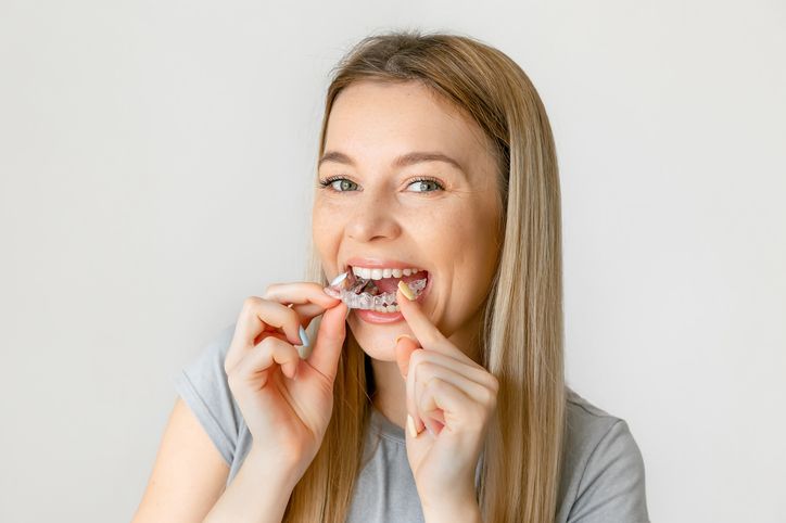 A woman is holding a clear brace in her mouth.