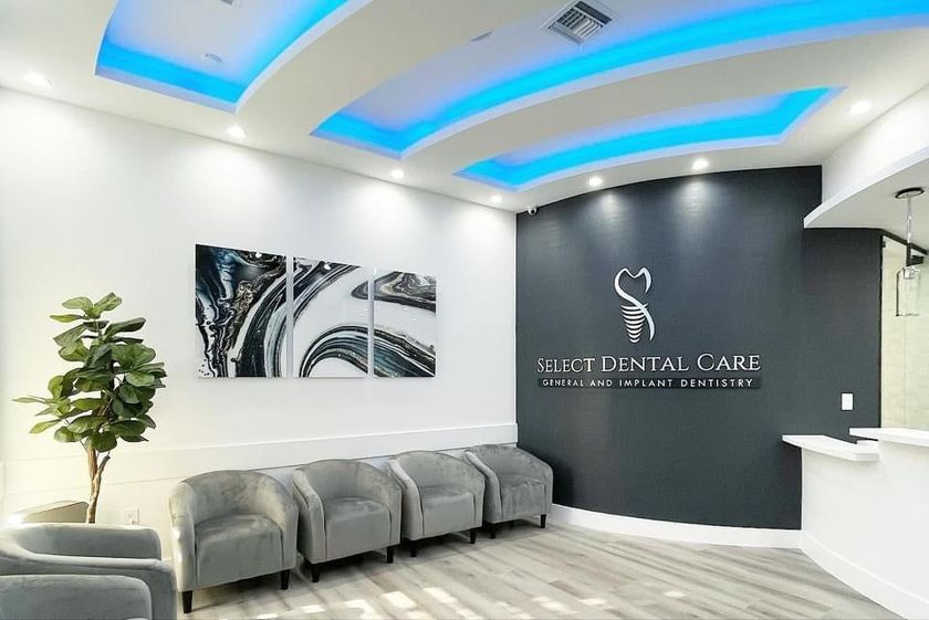 A waiting room at a dental office with chairs and a sign on the wall.