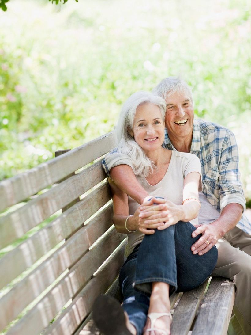 A man and a woman are sitting on a wooden bench.