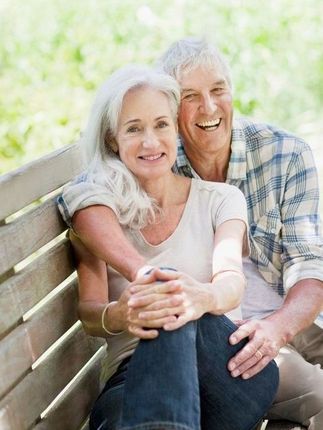 A man and a woman are sitting on a wooden bench.