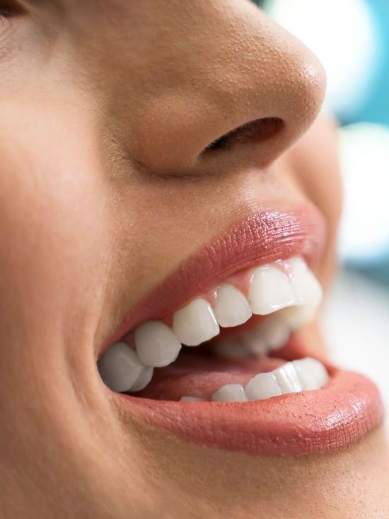 A close up of a woman 's mouth with white teeth and red lips.