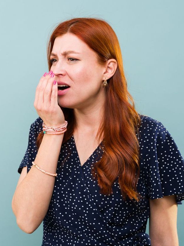 A woman with red hair is covering her mouth with her hand.