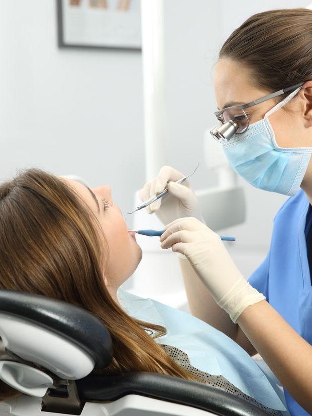 A woman is getting her teeth examined by a dentist