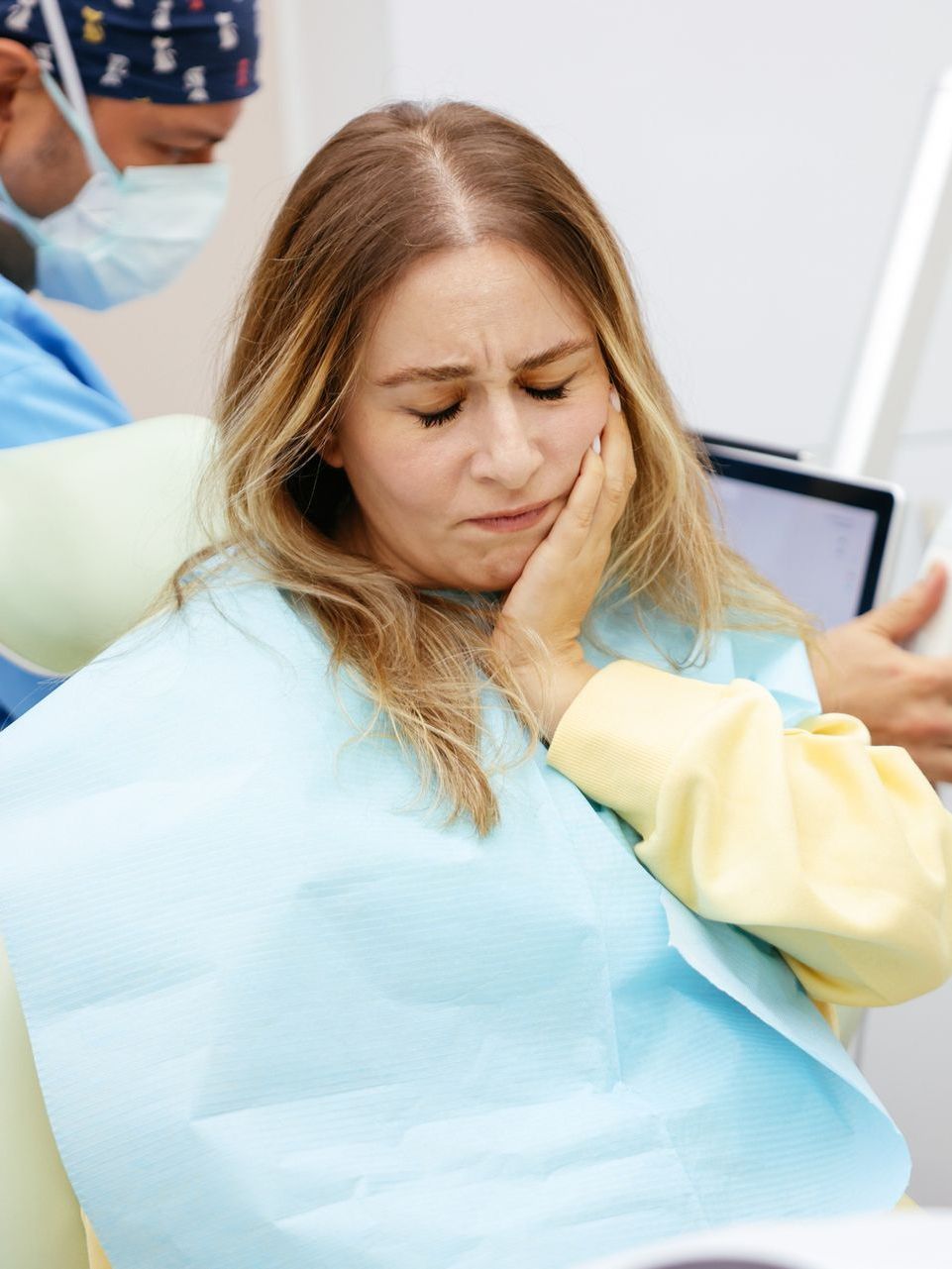 A woman is sitting in a dental chair with a toothache.