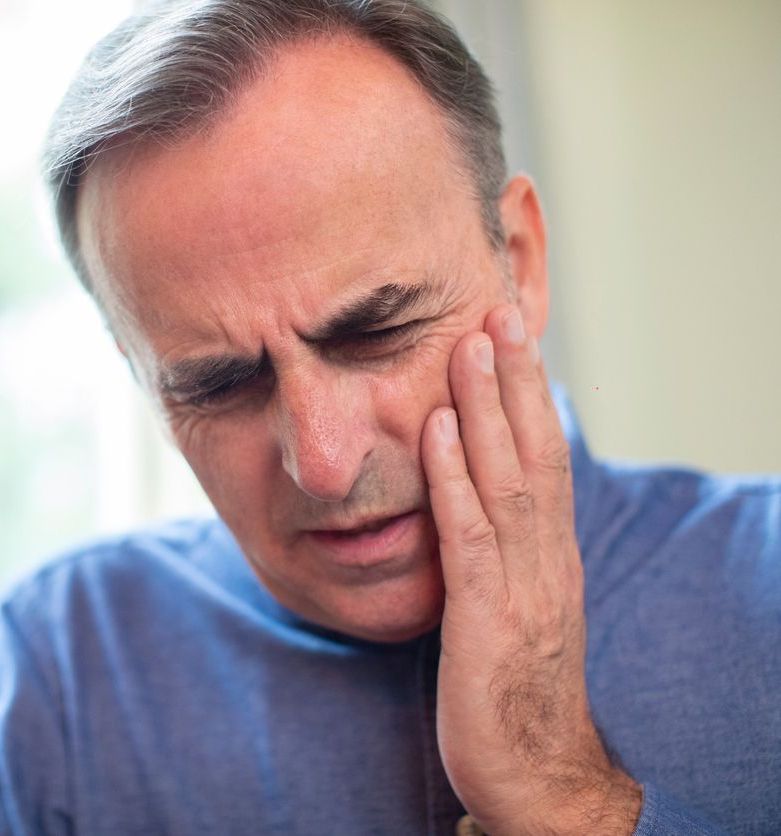 A man is holding his face in pain because of a toothache.