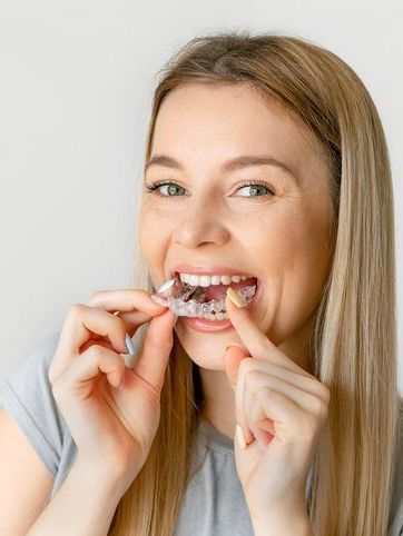 A woman is holding a clear brace in her mouth.