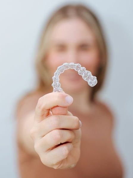 A woman is holding a clear brace in her hand.