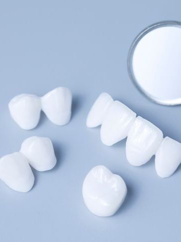 A group of white teeth and a dental mirror on a blue surface.