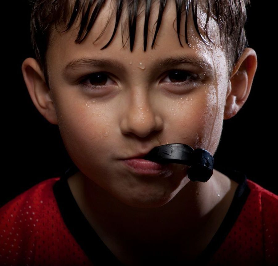 A young boy wearing a mouth guard looks at the camera