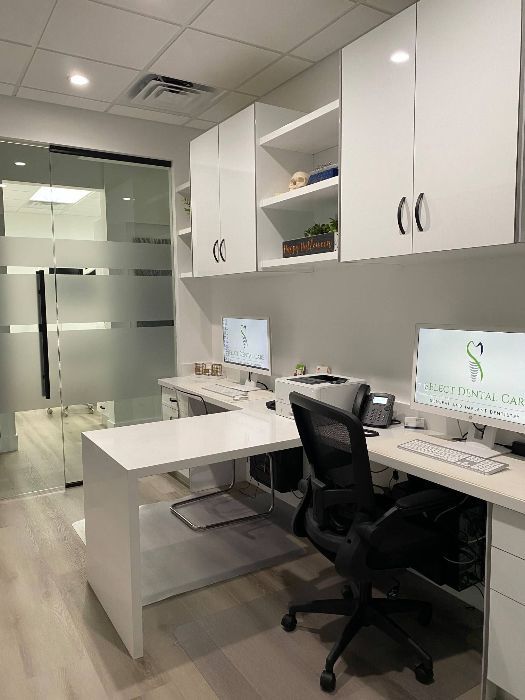 A desk with a computer on it and a chair in an office.