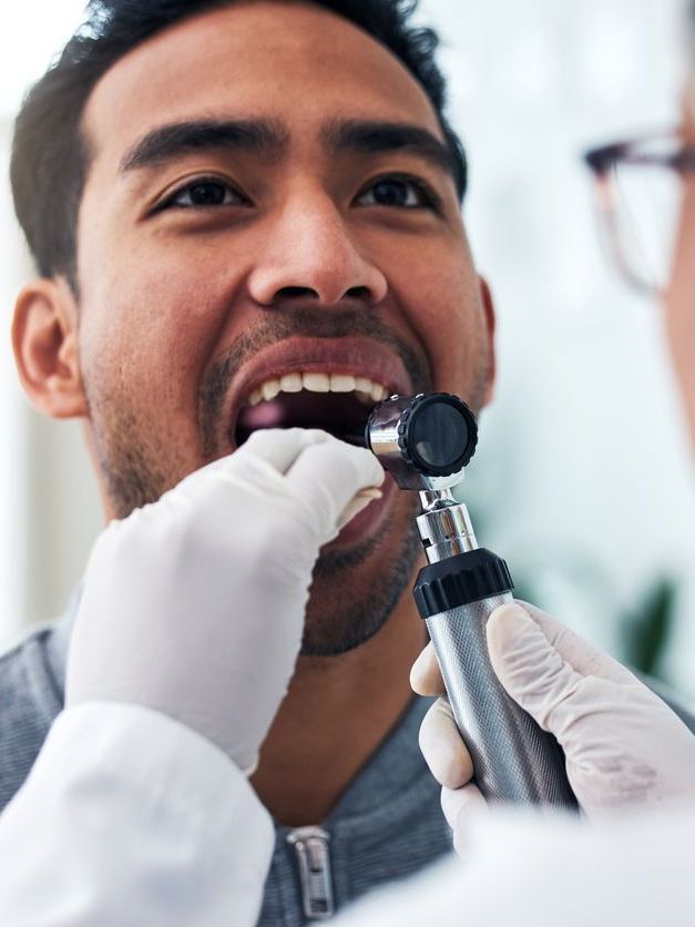 A man is getting his throat examined by a doctor