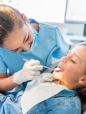 A little girl is getting her teeth examined by a dentist.