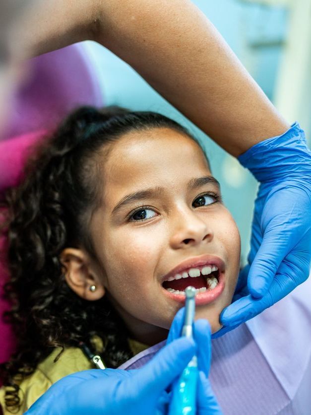 A little girl is getting her teeth examined by a dentist.