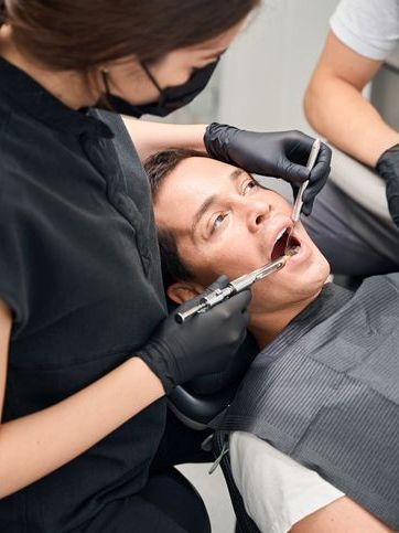 A man is getting his teeth examined by a female dentist.