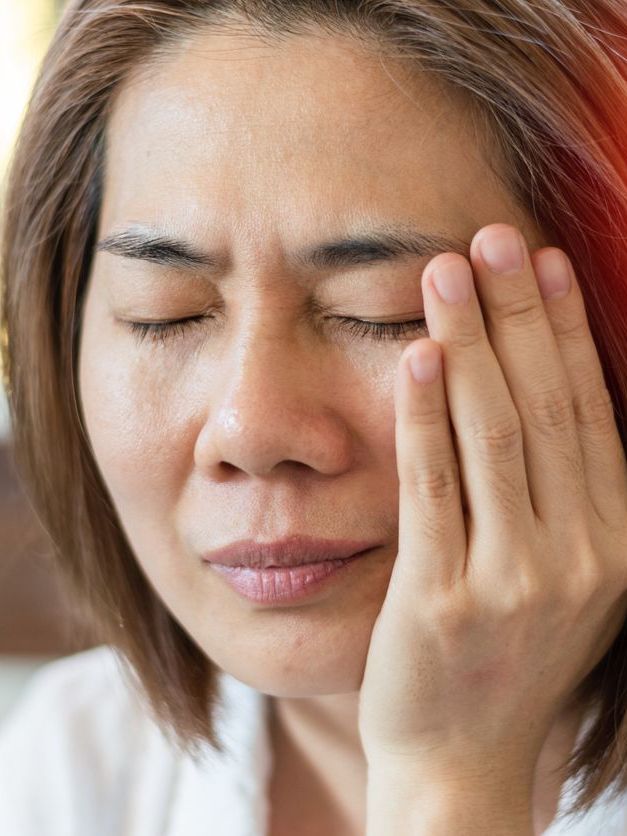 A woman is holding her head in pain because of a headache.