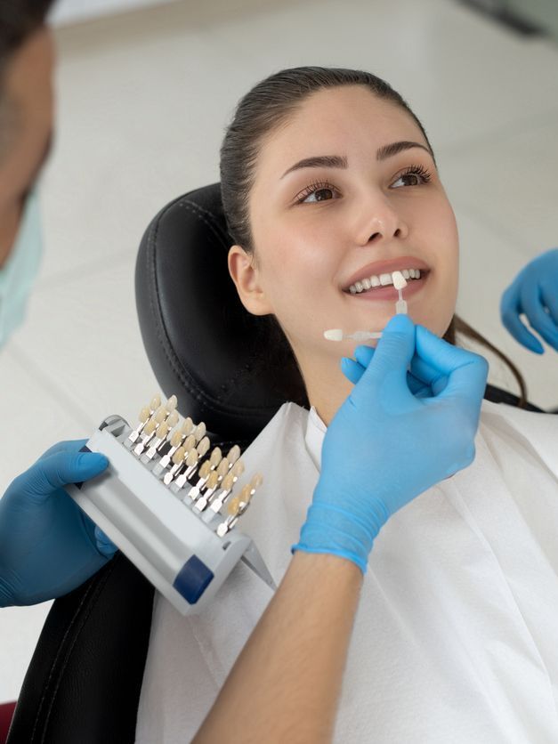 A woman is sitting in a dental chair while a dentist examines her teeth.