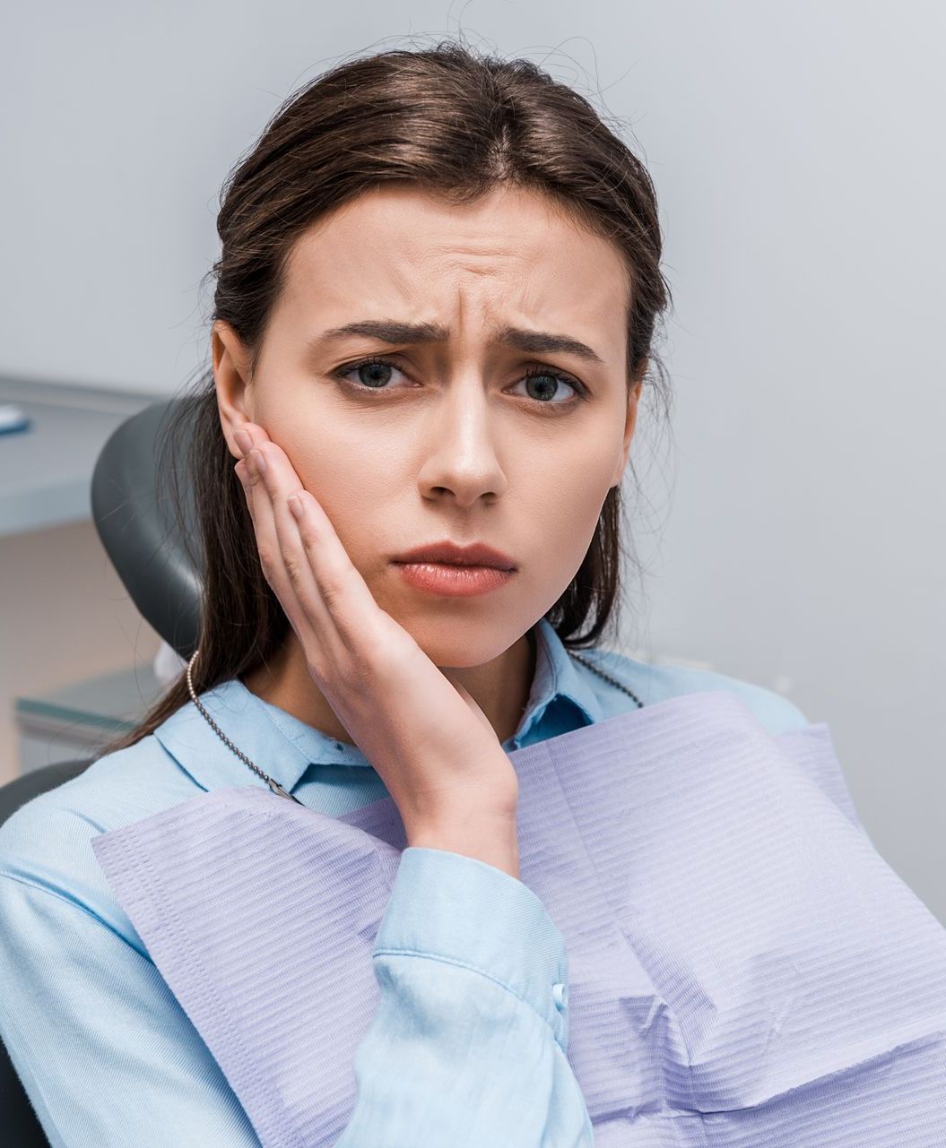 A woman is sitting in a dental chair with a toothache.