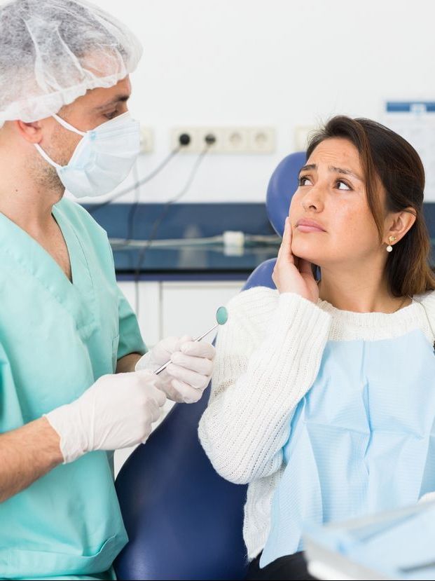 A woman is sitting in a dental chair with a toothache.