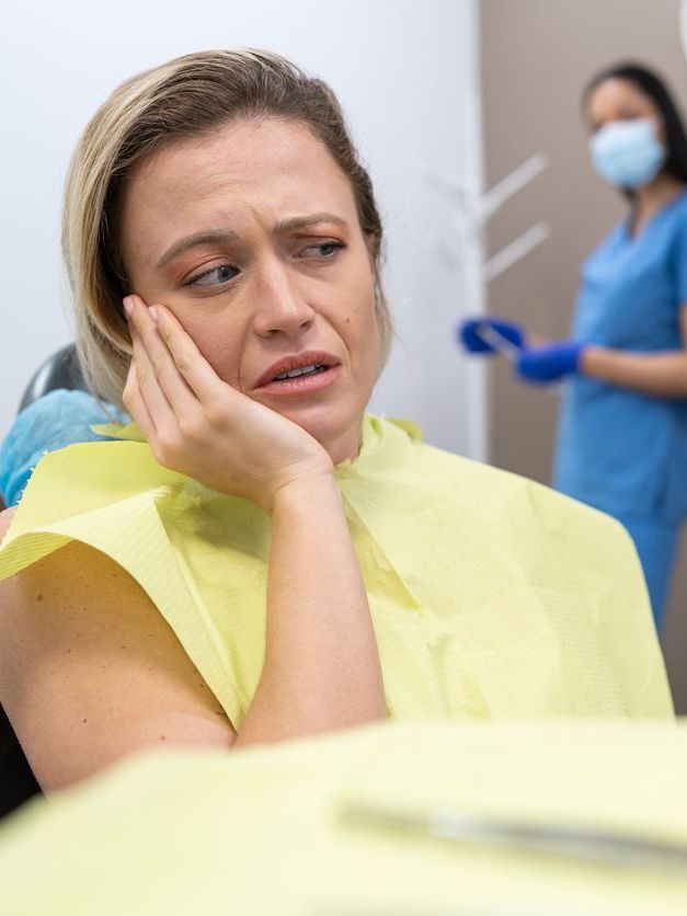 A woman is sitting in a dental chair with a toothache.