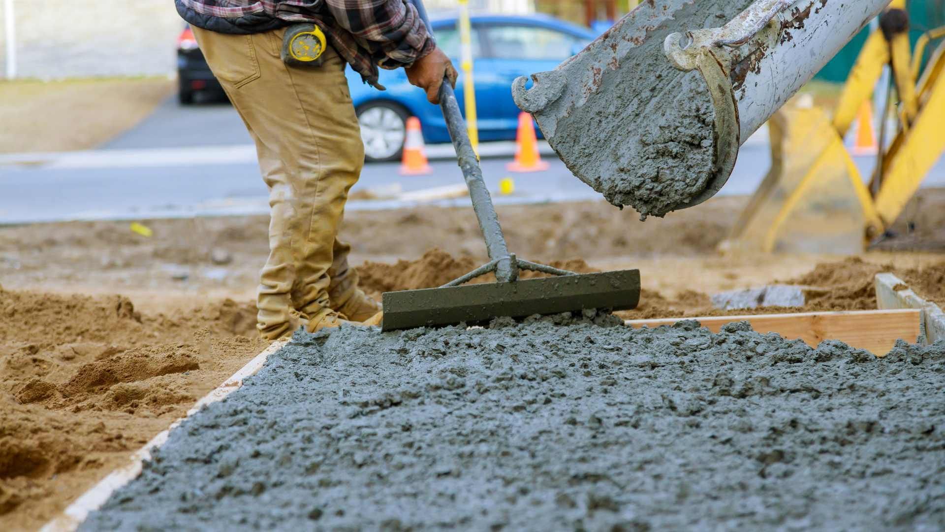 A man is raking concrete on a construction site.