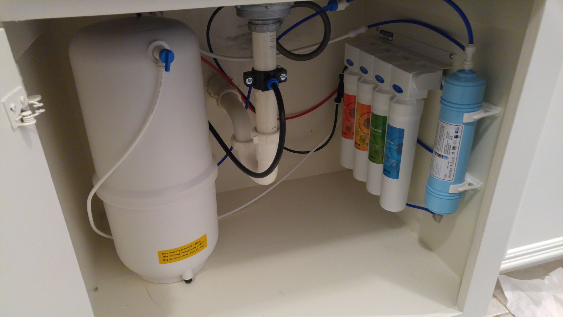 Under-sink Watts Quick-Change Reverse Osmosis system with Bio++ alkaline filter, pressurized tank, air-gap faucet tubing, and a legal drain saddle tap installation.
