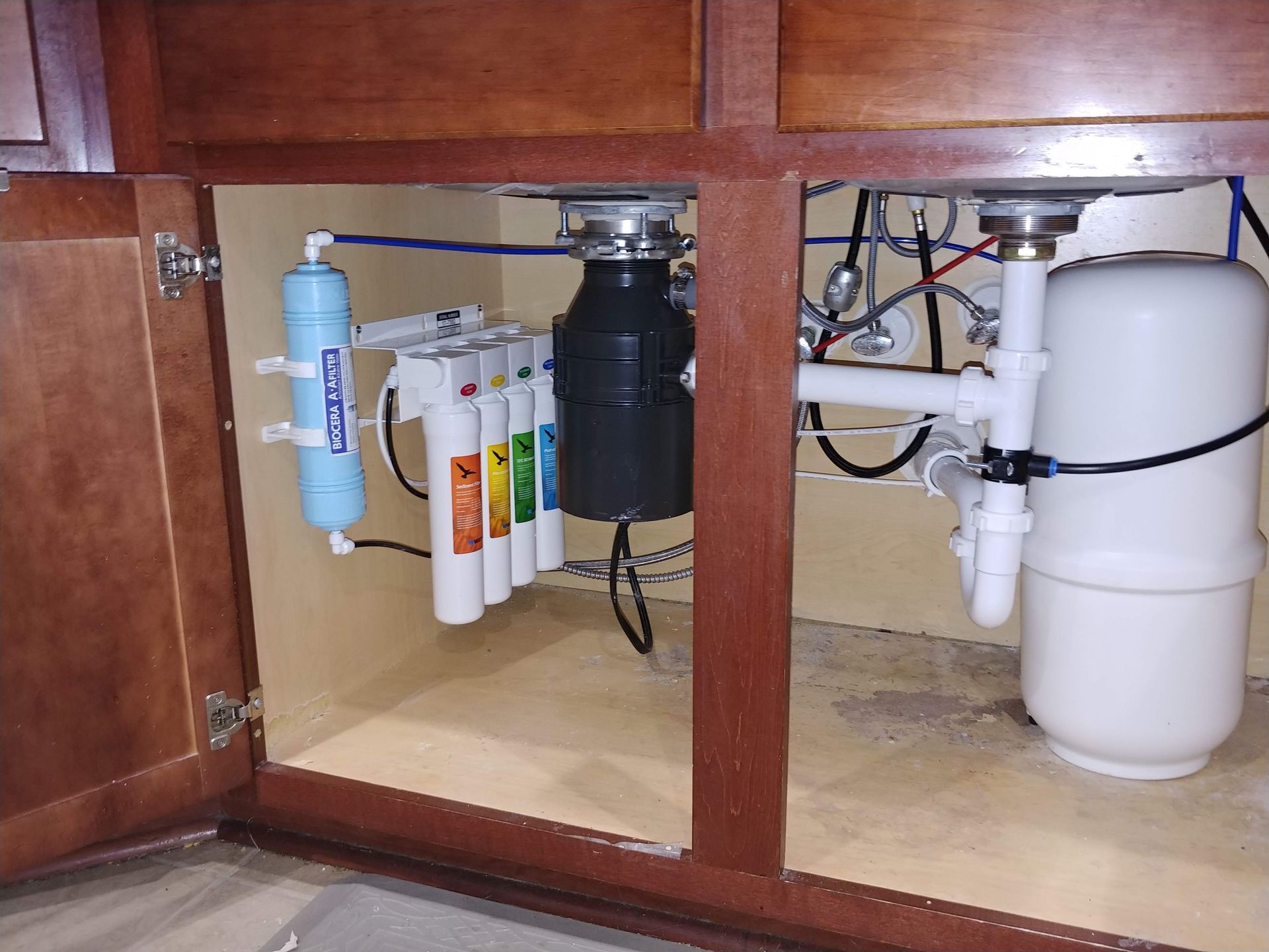 Under-sink Watts Quick-Change reverse osmosis system with BIO++ post-filter installed next to a garbage disposal in Waller, Texas.