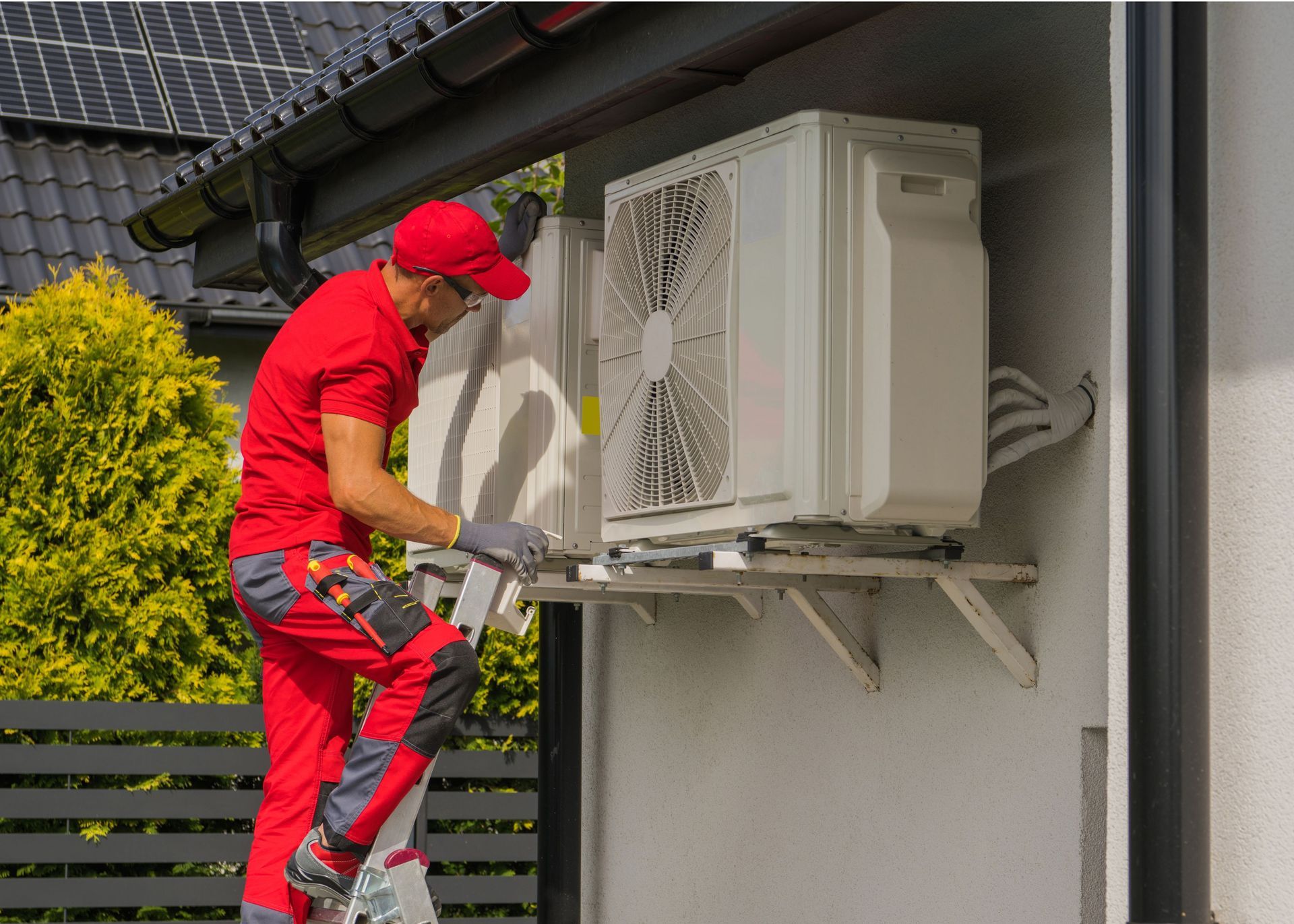 A man is installing an air conditioner on the side of a building.