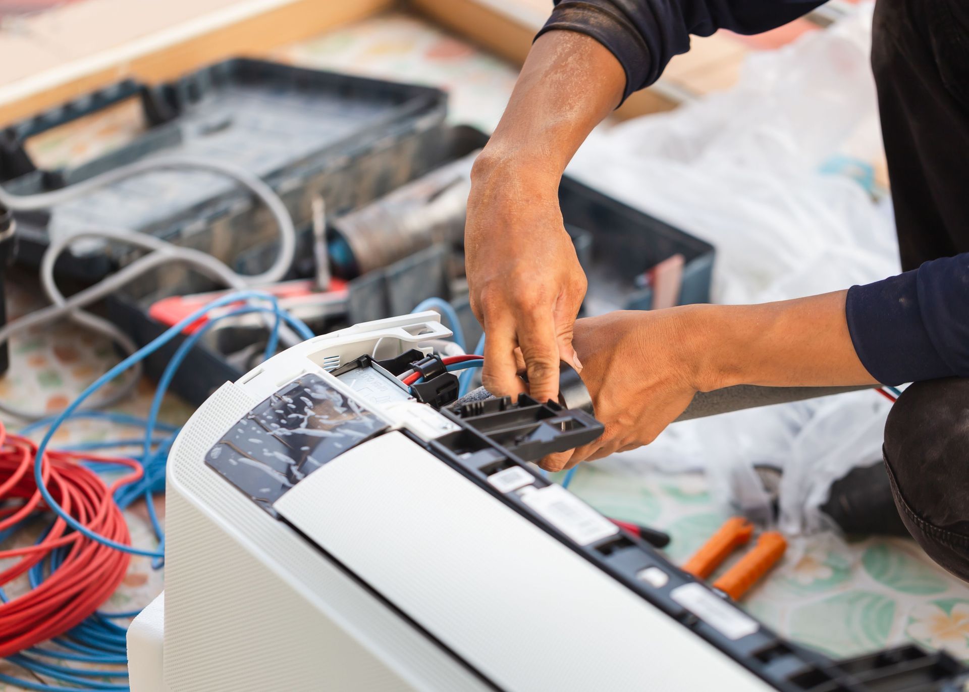 A man is fixing an air conditioner on the floor.