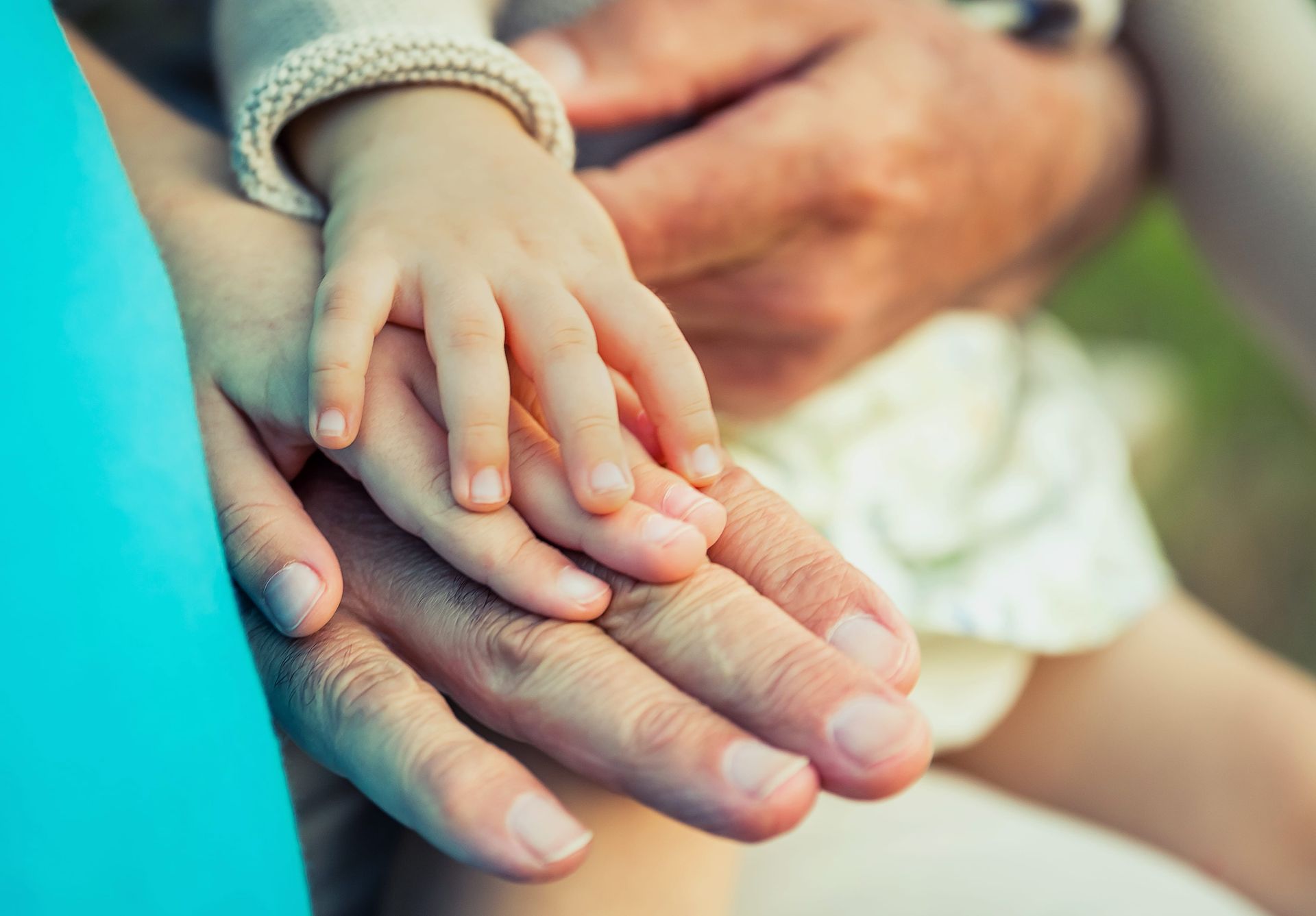 A close-up of a small child's hand resting on top of a larger adult hand, representing connection and support.