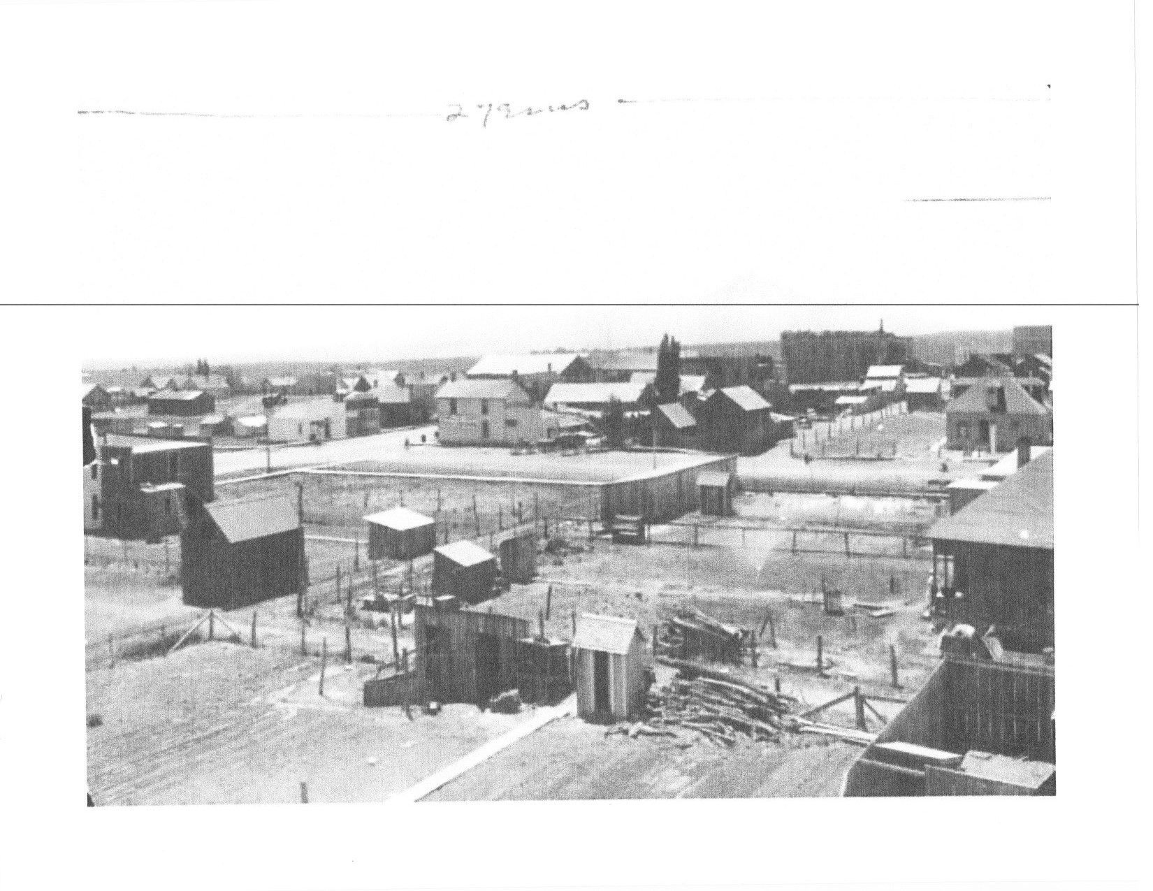 A black and white photo of a small town with a lot of buildings.