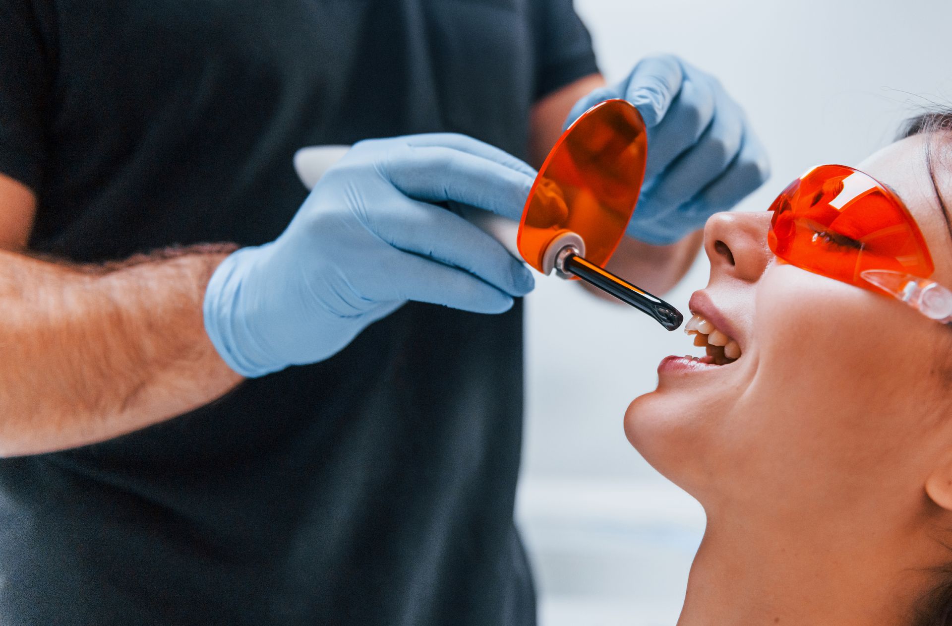 A woman is getting her teeth whitened by a dentist.