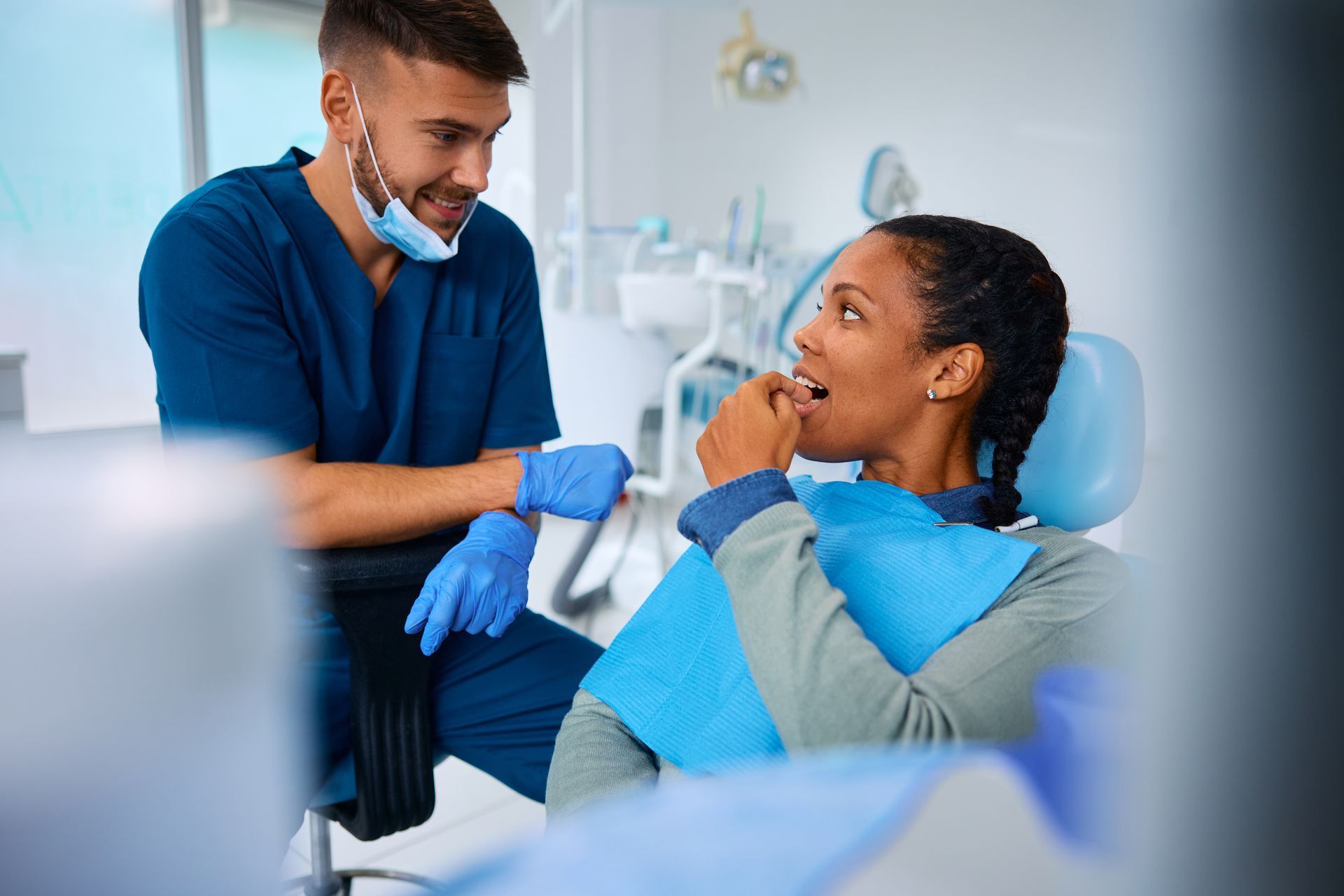 A woman is sitting in a dental chair talking to a dentist.