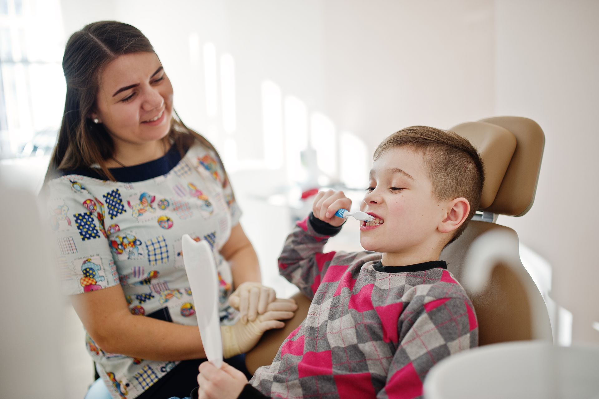 A young boy is brushing his teeth at the dentist.