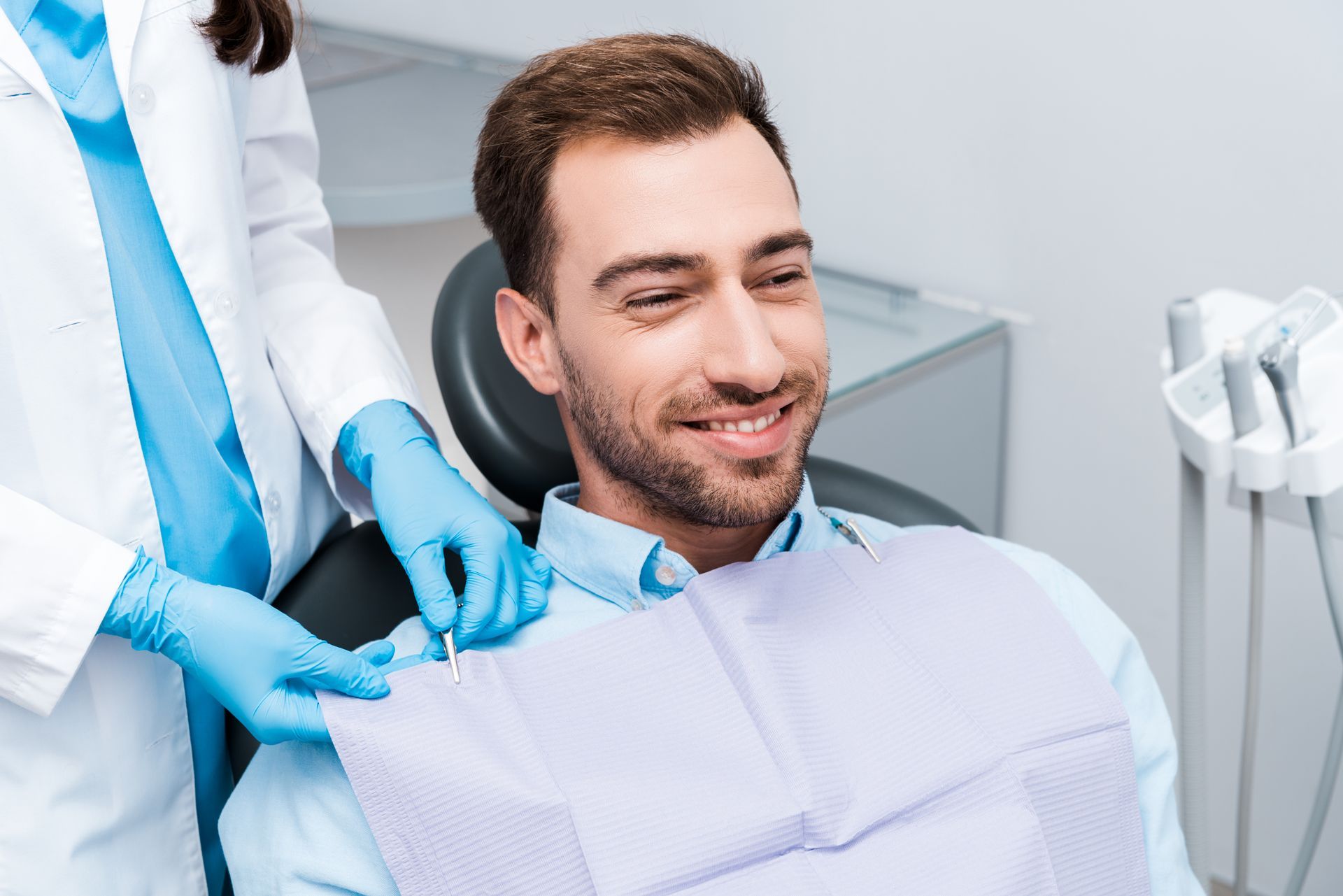 A man is sitting in a dental chair while a dentist examines his teeth.