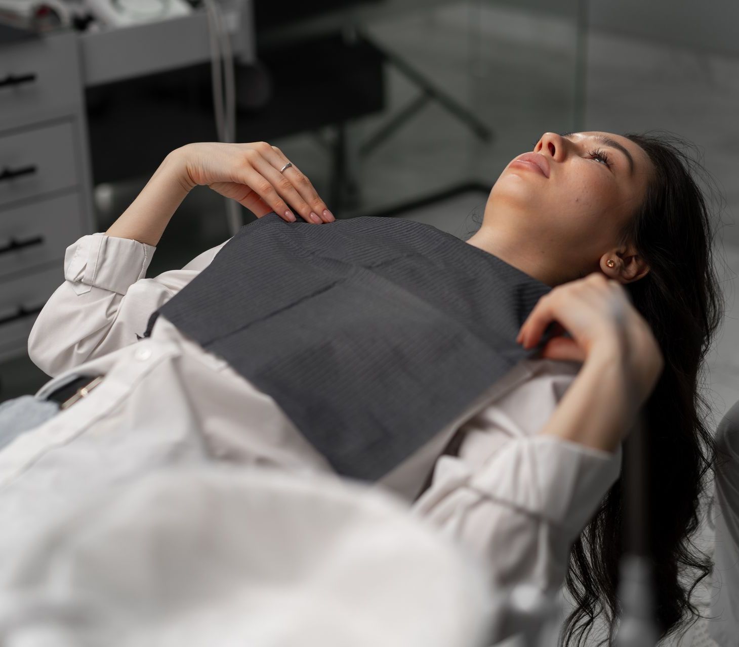 A woman is laying in a dental chair with her eyes closed