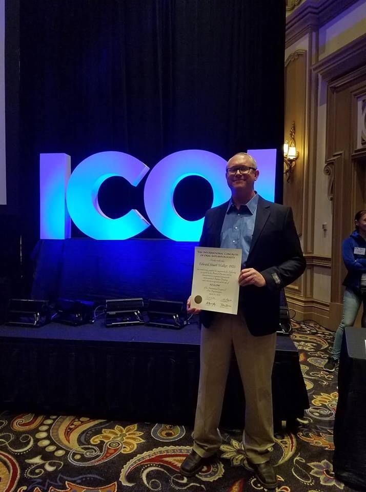 A man is holding a certificate in front of a large ico sign