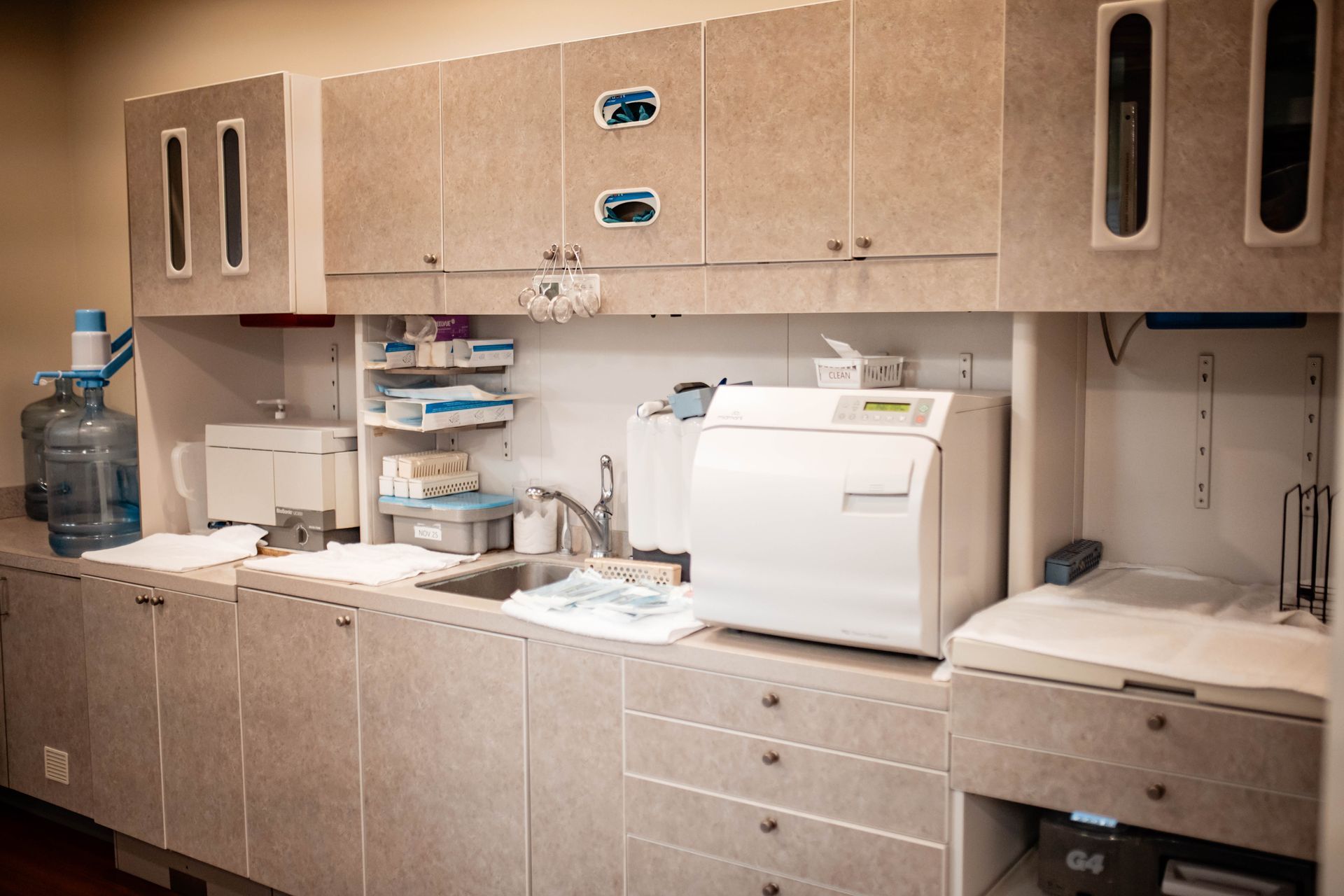 A kitchen with cabinets , drawers , a sink , and a sterilizer.