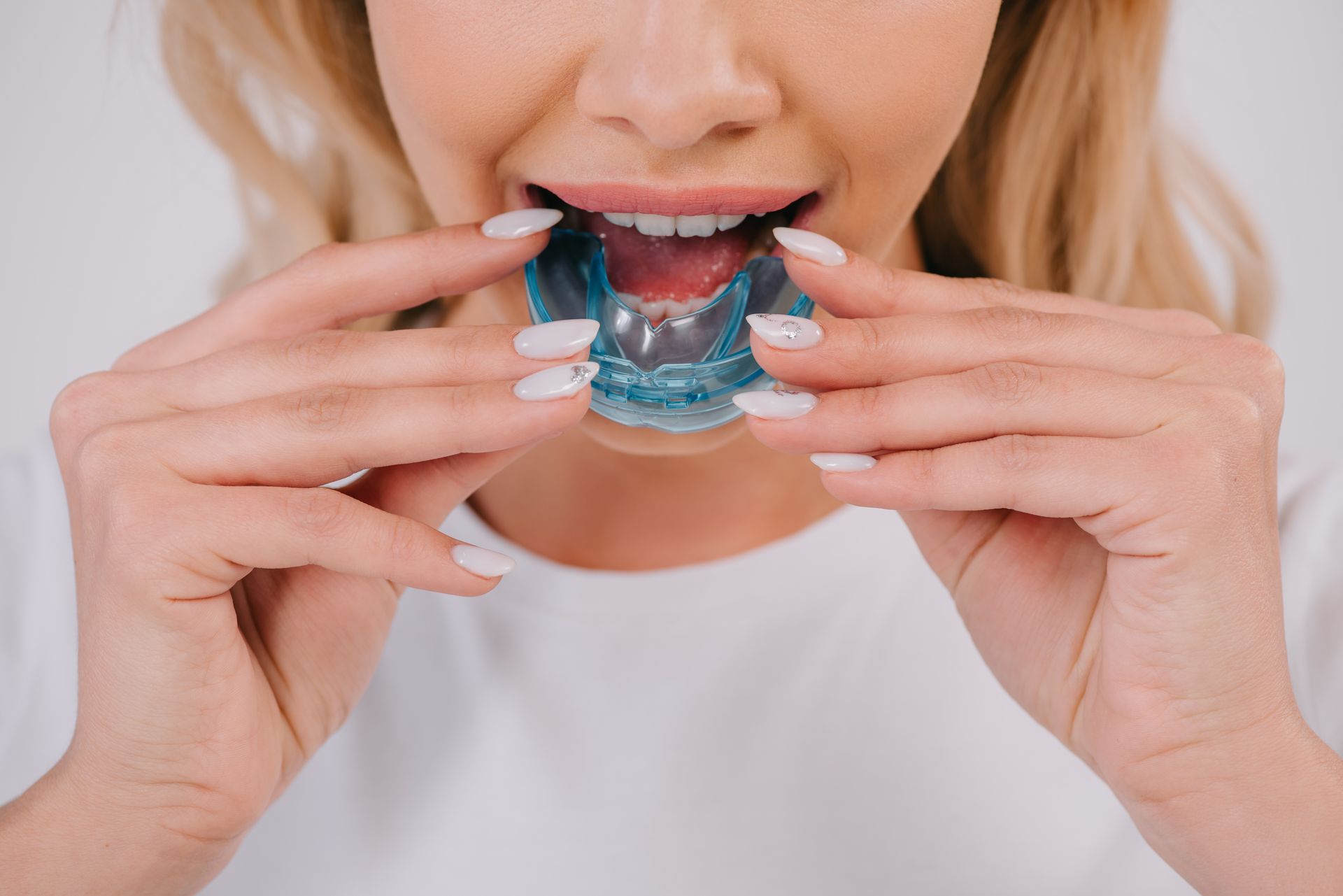 A woman is holding a mouth guard in her mouth.