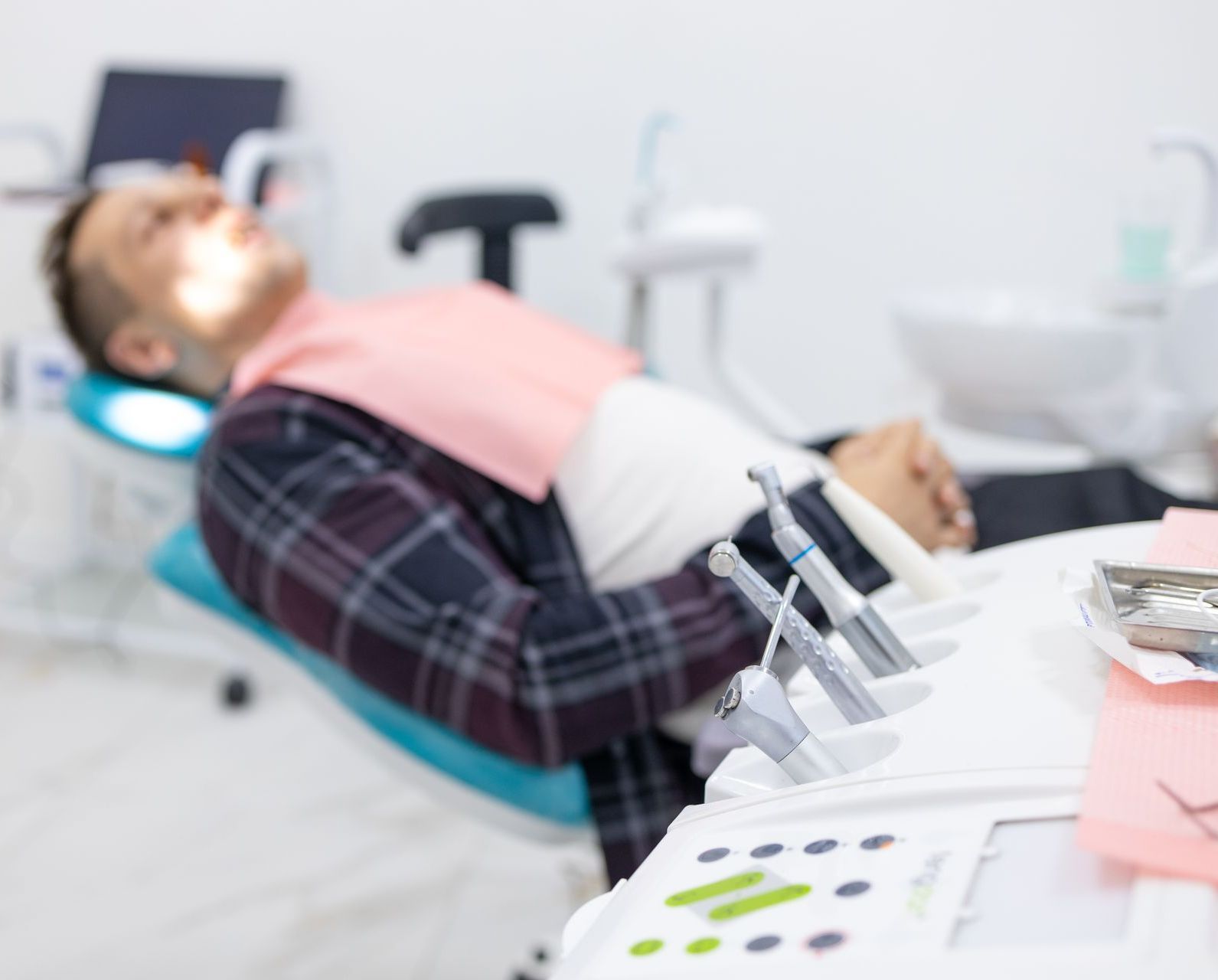 A man is laying in a dental chair with his eyes closed