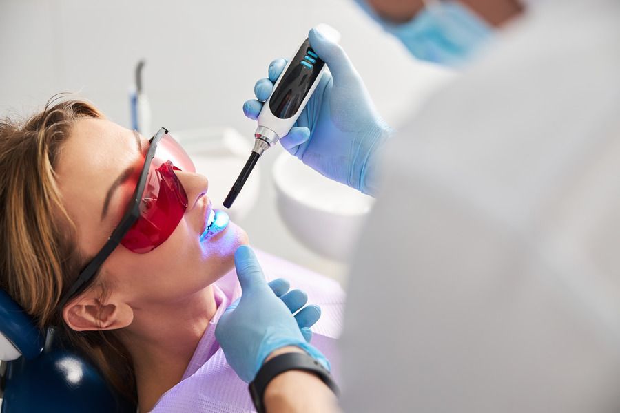 A woman is getting her teeth whitened by a dentist.