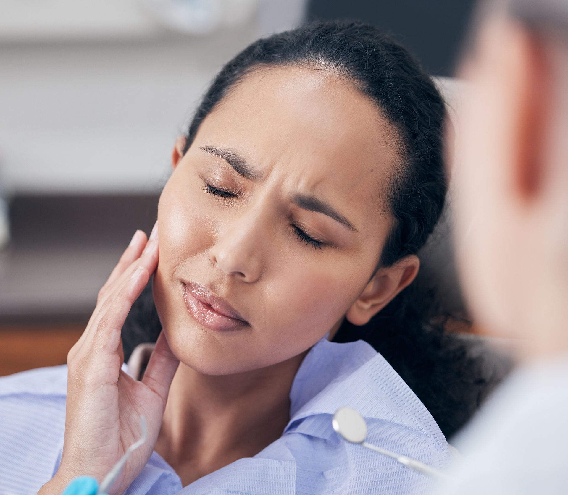 A woman is sitting in a dental chair with a toothache.