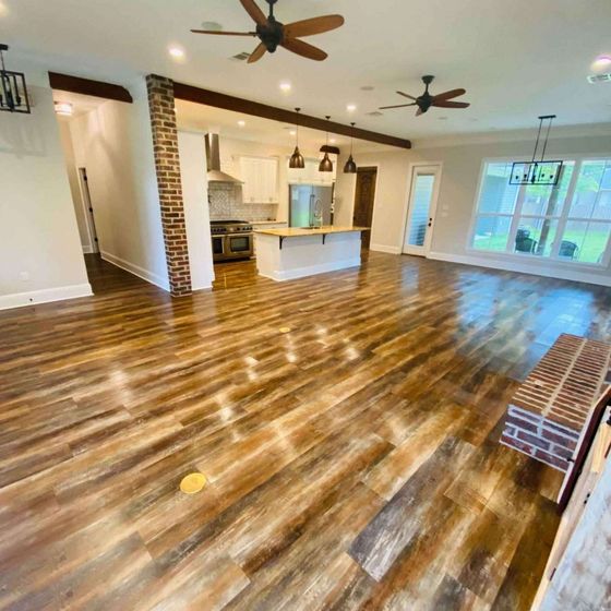 Spacious open-concept living space with wood flooring, kitchen, and exposed brick accents.