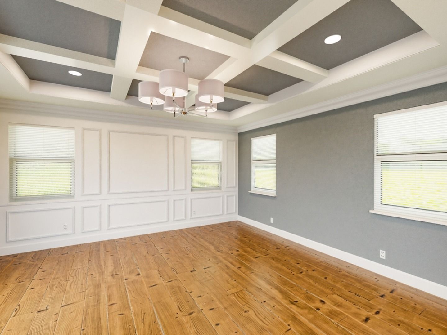 Empty room with wood floors, molding, and a coffered ceiling with a chandelier.