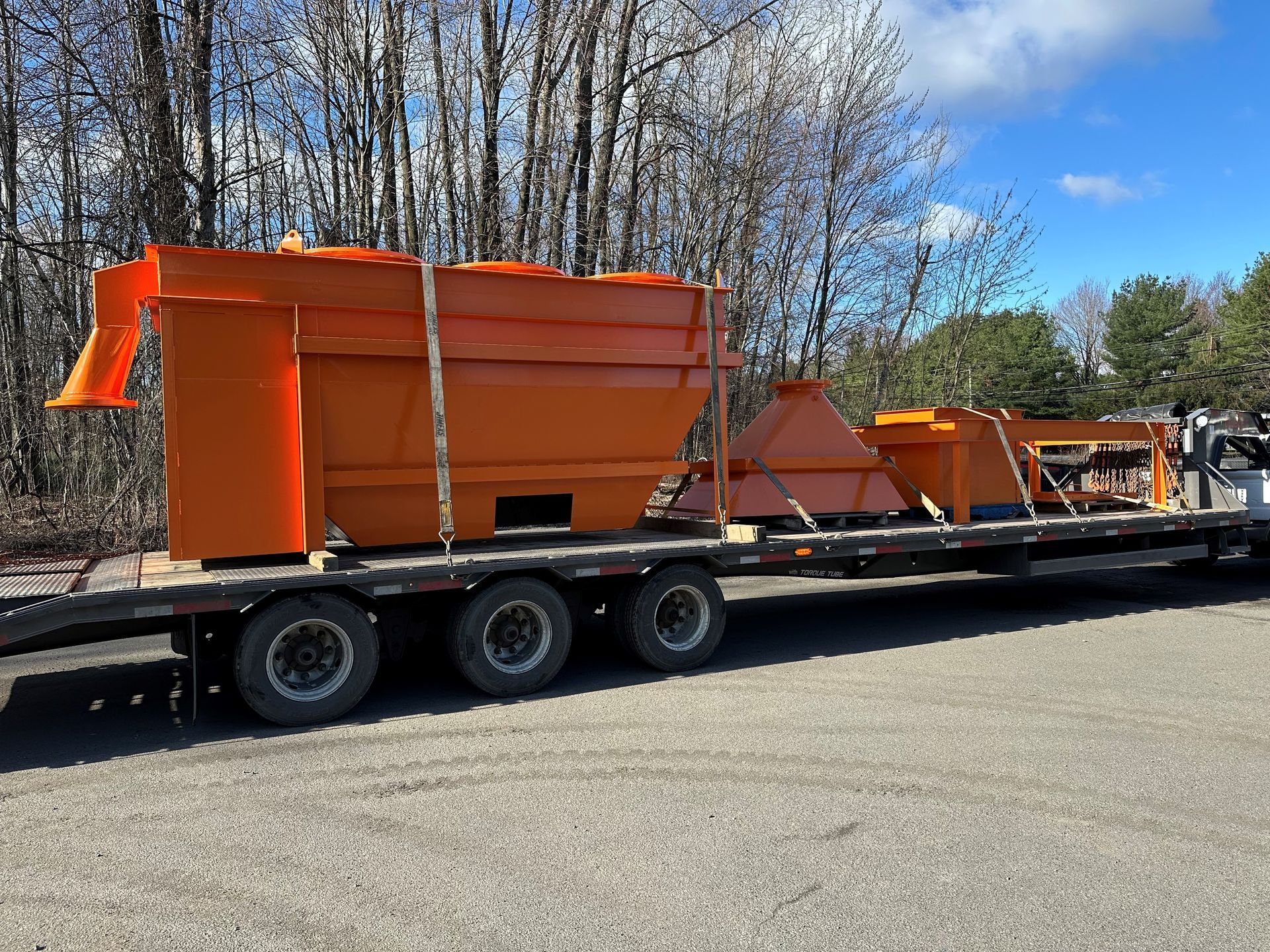 Machines industrielles orange chargées sur une remorque à plateau.