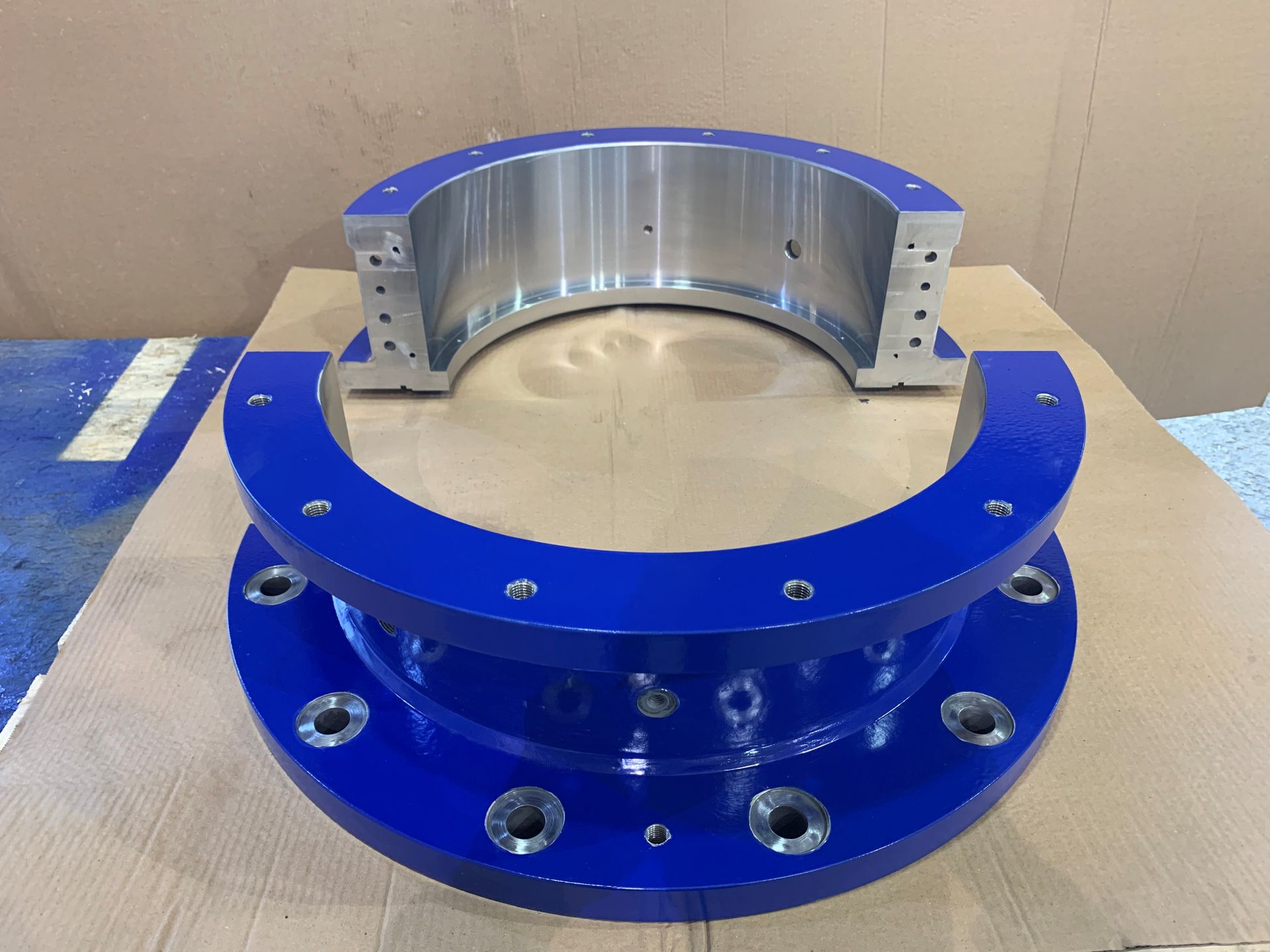 Palier métallique semi-circulaire bleu et argent avec trous de boulons, probablement destiné à des machines ou à un usage industriel.